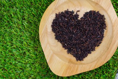 Yakın çekim kahverengi pirinç veya kase yeşil çimenlerin üzerinde ahşap doku üzerinde sağlıklı riceberry organik gıda