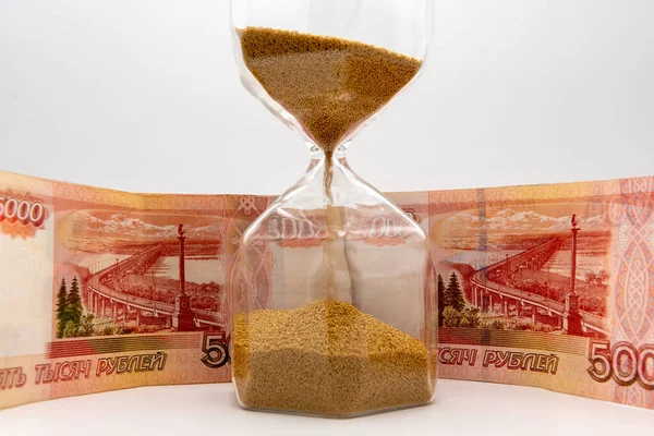 Timglas och ryska sedlar på vit bakgrundstid pengar — Stockfoto