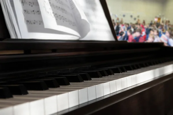 Piano and notes at the concert and blurred background the audience in the hall — Stock Photo, Image