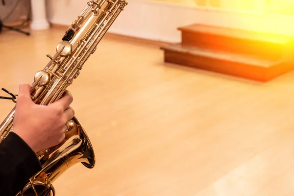 Hand of musician playing jazz saxophone during live performance on stage
