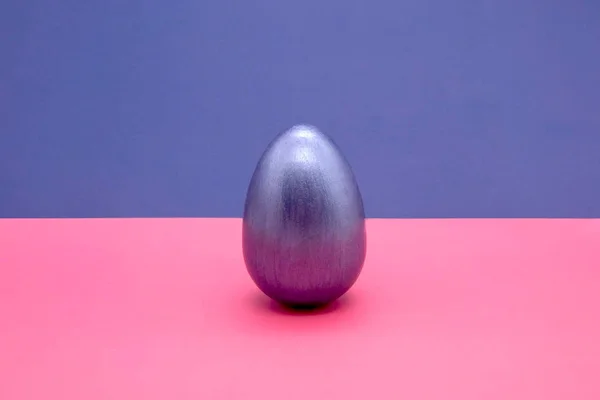 Egy kék húsvéti tojás kék és rózsaszín háttérrel — Stock Fotó