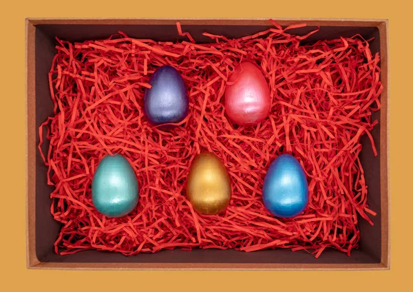 Uova di Pasqua variopinte in una scatola su rosso — Foto Stock