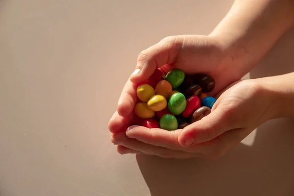 Doces coloridos, açúcar, muito, não saudável nas mãos de uma criança — Fotografia de Stock