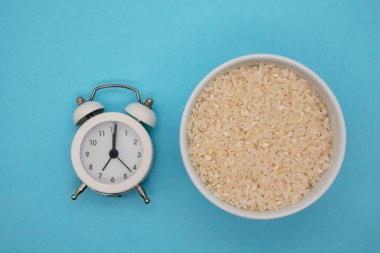 Sağlıklı yemek için kase ve saatin içindeki pirinç manzarası tam zamanında.