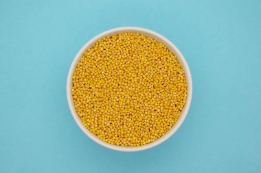 Beyaz seramik kasedeki kuru darılar mavi üzerine izole edilmiş..