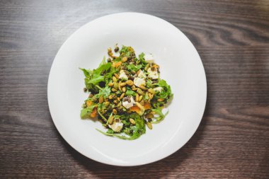 Bir tabak koyu ahşap bir masa üzerinde sağlıklı kabak ve mercimek salatası ile.