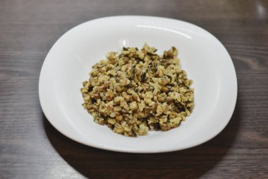 Beyaz bir tabak pirinç ve mercimek koyu ahşap bir masa üzerinde yapılan sağlıklı Ayurveda çanak khichdi ile.