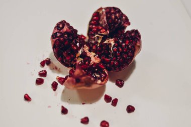 Koyu kırmızı tohumları ile açık nar beyaz bir yüzeye kesmek.