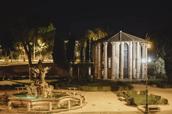 ROMA, ITALIA - CIRCA OCTUBRE 2016: un parque con fuente y antiguas columnas romanas en el centro histórico de Roma, Italia por la noche alrededor de octubre 2016 . — Foto de Stock