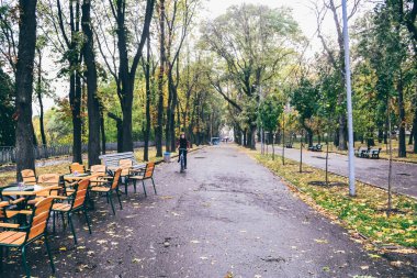 Kiev, Ukrayna - Ekim 2011 yaklaşık: ahşap sandalye ve masa, Kiev, Ukrayna cicra Ekim 2011 eski kasabasında kuru sarı ve turuncu yaprak ağaçları ile sonbahar Park açık bir kafe.