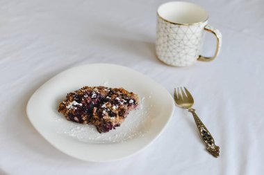 Ücretsiz muz yulaf ezmesi kek çilek bir halk ile beyaz bir tabak ve altın süsleme ile bir fincan ile sağlıklı şekersiz ve un.