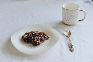 Ücretsiz muz yulaf ezmesi kek çilek bir halk ile beyaz bir tabak ve altın süsleme ile bir fincan ile sağlıklı şekersiz ve un.