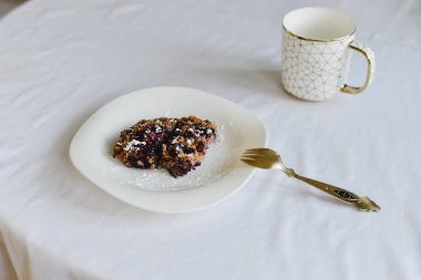 Ücretsiz muz yulaf ezmesi kek çilek bir halk ile beyaz bir tabak ve altın süsleme ile bir fincan ile sağlıklı şekersiz ve un.