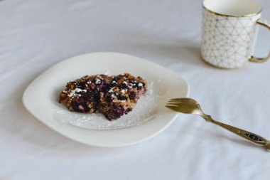 Ücretsiz muz yulaf ezmesi kek çilek bir halk ile beyaz bir tabak ve altın süsleme ile bir fincan ile sağlıklı şekersiz ve un.