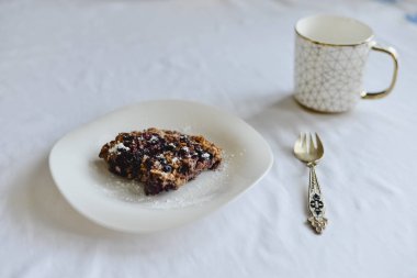 Ücretsiz muz yulaf ezmesi kek çilek bir halk ile beyaz bir tabak ve altın süsleme ile bir fincan ile sağlıklı şekersiz ve un.