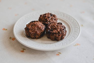 Ücretsiz muz yulaf ezmesi muffins beyaz bir plaka üzerinde gri bir masa örtüsü üzerinde yaban mersini ile sağlıklı şekersiz ve un.