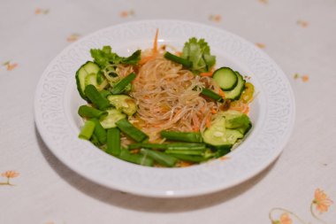 Asya yemek: cam salatalık, maydanoz ve taze soğan gri keten masa örtüsü üzerinde beyaz bir plaka ile servis erişte.