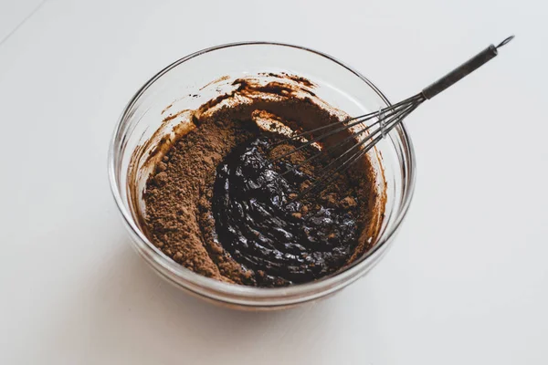 Een proces van het maken van chocolade saus: een glazen kom met chocolade mengsel op het witte oppervlak. — Stockfoto