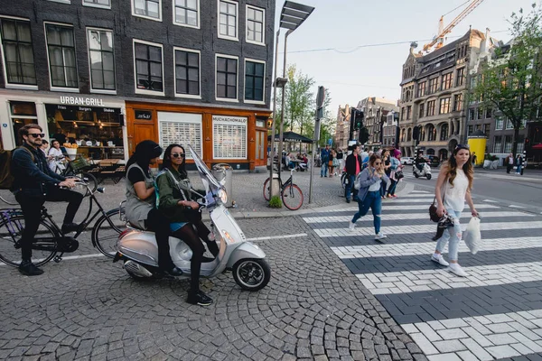 Amsterdam - Circa juni 2017: flickor på en motocycle på gatan längs Göta kanal med traditionella holländska husfasader i centrala Amsterdam, Nederländerna i juni 2017. — Stockfoto