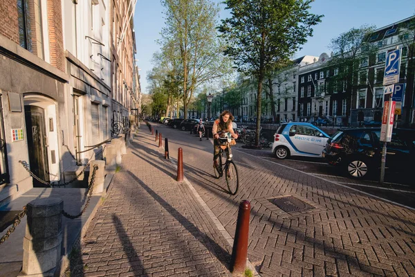 AMSTERDÃO - CIRCA JUNE 2017: um ciclista na rua ao longo do canal com fachadas tradicionais holandesas no centro de Amsterdã, Holanda, em junho de 2017 . — Fotografia de Stock