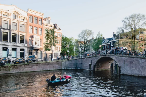 AMSTERDAM - CIRCA JUNIO 2017: vista clásica de un canal con barcos y puente con casas holandesas tradicionales en los terraplenes de Ámsterdam, Holanda en junio de 2017 . — Foto de Stock