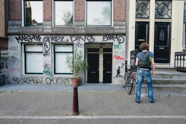 Amsterdam - Circa juni 2017: se av en traditionell holländska byggnad fasad med graffiti och street i centrala Amsterdam, Nederländerna i juni 2017. — Stockfoto