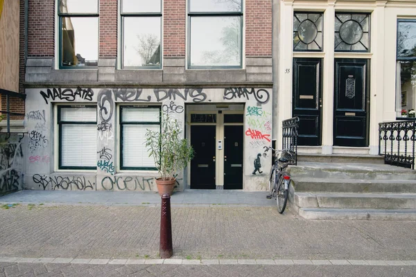 Amsterdam - Circa juni 2017: se av en traditionell holländska byggnad fasad med graffiti och street i centrala Amsterdam, Nederländerna i juni 2017. — Stockfoto