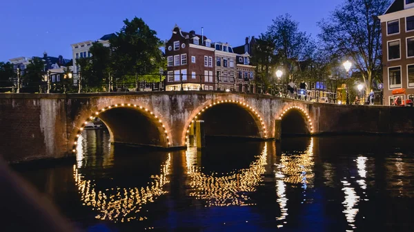 オランダのアムステルダムで、2017 年 6 月の夜間運河上のライトを有する橋のアムステルダム - 2017 年 6 月頃: ビュー. — ストック写真