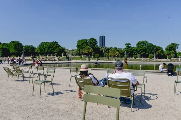 Paris, Franciaország - Circa 2017. június: az emberek többi a hagyományos zöld székek a Luxembourg-kert, egy napsütéses napon-Párizs, Franciaország-június 2017-ben. — Stock Fotó