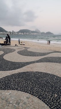Rio De Janeiro, Brezilya - Eylül 2019: Copacabana Plajı 'ndaki insanlar gün batımında gökyüzü bulutlu.