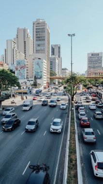 Sao Paulo, Brezilya - Eylül 2019: Sıcak ve güneşli bir günde Sao Paulo şehir merkezinde birçok araba ve yüksek binalarla dolu yoğun bir yol.