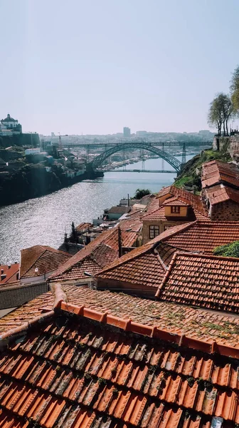 ポルト ポルトガル 2020年3月13日 ポルトの歴史的中心部にあるドゥオーロ川の堤防上の伝統的なポルトガルの家の赤いタイル張りの屋根と晴れた日に後ろのルイスI橋 — ストック写真