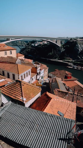 ポルト ポルトガル 2020年3月13日 ポルトの歴史的中心部にあるドゥロ川の堤防上の伝統的なポルトガルの家の赤いタイル張りの屋根と晴れた日に後ろのInfante橋 — ストック写真