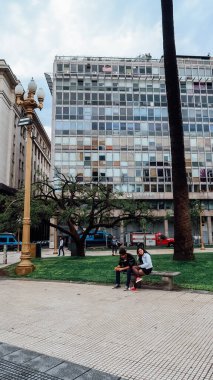 BUENOS AIRES, ARGENTINA - CIRCA ECTOBER 2019: İnsanlar gri yağmurlu bir bahar gününde Buenos Aires 'in merkezinde meydanda otururlar.