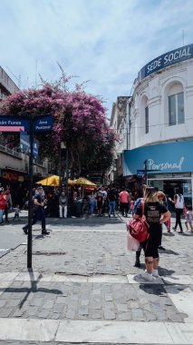 CORDOBA, ARGENTINA - CIRCA ECTOBER 2019: Dean Funes yayalar caddesinde dükkanları, dükkanları ve çiçek açan mor çiçekleri olan insanlar.