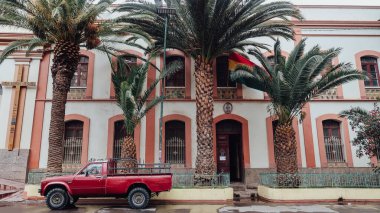 TUPIZA, BOLIVIA - CIRCA NOVEMBER 2019: red car parked near facade of Our Lady of the Candelaria catholic cathedral in small town Tupiza. clipart
