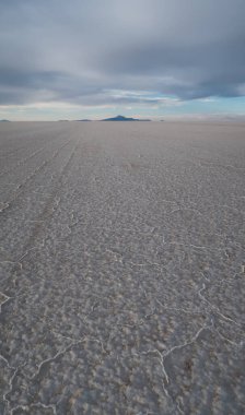 UYUNI, BOLIVIA - CIRCA Kasım 2019: Bulutlu gökyüzü ile gün batımında Salar de Uyuni 'nin sonsuz boş tuz çölü.