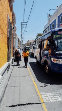 AREQUIPA, PERU - CIRCA NOVEMBER 2019: Mavi gökyüzü güneşli bir günde Arequipa 'nın merkezinde sarı cepheli koloni binaları olan küçük dar bir sokak.