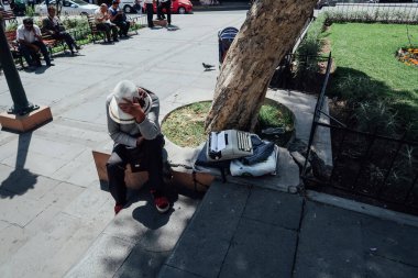 AREQUIPA, PERU - CIRCA NOVEMBER 2019: Güneşli bir günde Plaza Espana 'da daktiloyla şapkalı son sınıf öğrencisi gölgede oturuyor.