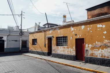 AREQUIPA, PERU - CIRCA NOVEMBER 2019: Mavi gökyüzü olan güneşli bir günde Arequipa 'nın merkezinde eski sarı cepheli, dar bir sokak.