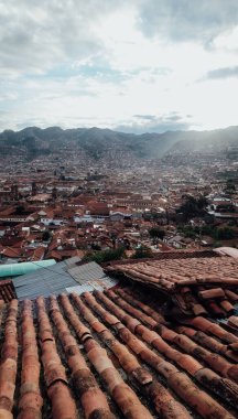 CUSCO, PERU - CIRCA NOVEMBER 2019: Dağlarla çevrili turuncu kiremitli çatıları olan eski Cusco kasabasının havadan görünüşü.