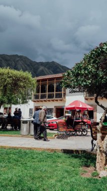 CUSCO, PERU - CIRCA NOVEMBER 2019: İnsanlar bulutlu bir günde Cusco 'nun etrafındaki Kutsal Vadi' nin dağlarındaki sessiz bir sömürge köyünün ana meydanında vakit geçirirler..