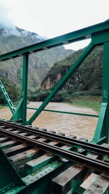 MACHU PICCHU, PERU - CIRCA Kasım 2019: Machu Picchu Pueblo 'ya giden tren yolu boyunca hızlı nehri geçen yeşil köprü.