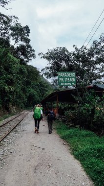 MACHU PICCHU, PERU - CIRCA Kasım 2019: Yürüyüşçüler Machu Picchu Pueblo 'ya yeşil dağlarla demiryolu hattına giderler.