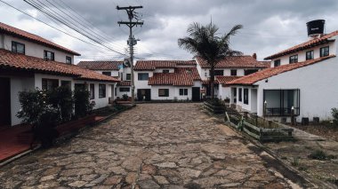 GUATAVITA, COLOMBIA - NOVEMBER 28 2019: kaldırım taşı dar sokak ve beyaz renklere boyanmış binalar Guatavita 'daki eski bir koloni kasabasında bulutlu bir günde.