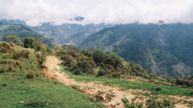 SANTANDER, COLOMBIA - CRCA Aralık 2019: Orman, yeşil tepeler ve bulutlu gökyüzü ile doğa yürüyüşü yolu.