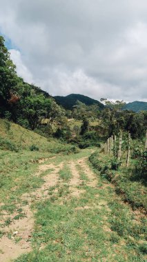 SANTANDER, COLOMBIA - CRCA Aralık 2019: Orman, yeşil tepeler ve bulutlu gökyüzü ile doğa yürüyüşü yolu.