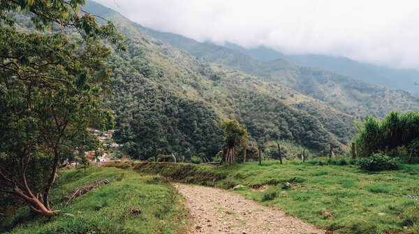 SANTANDER, COLOMBIA - CIRCA DECEMBER 2019: hiking path in natural landscape with forest and green hills and mountains on with cloudy sky.