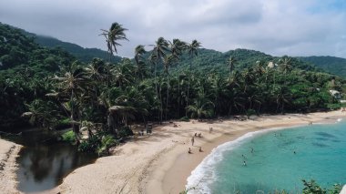 TAYRONA, COLOMBIA - CRCA Aralık 2019: Güneşli bir günde Tayrona Ulusal Parkı 'nda Cabo San Juan popüler plajı ve tropikal ormanlardaki Karayip denizinin turkuaz suları.
