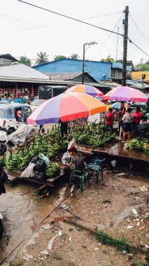 LETICIA, AMAZONAS, COLOMBIA - CRCA Aralık 2019: Yerel halk yağmurlu bir günde sokak pazarında yeşil muz ve diğer sebzeleri satıyor.